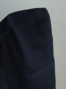 Close-up detail of the smooth fabric and seam of a minimalist navy pure color women's shirt.