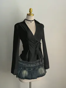 Detail of a black long-sleeved V-neck shirt with adjustable side lacing on a mannequin
