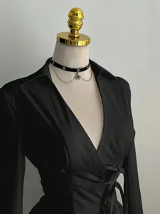 Detail view of a black deep V-neck shirt with waist-slimming design and elegant texture.