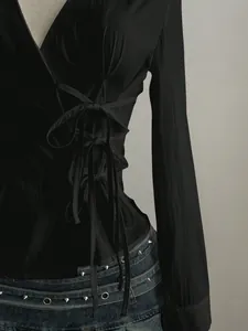 Detail view of black long-sleeved shirt with side lace-up corset design and V-neckline