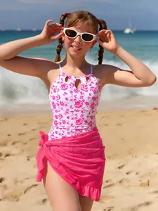 Close-up detail of girls' floral one-piece swimsuit with a pink mesh wrap at beach