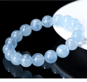 Macro view of a natural light blue aquamarine beaded bracelet on a black reflective surface