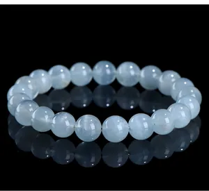 Macro view of natural light blue aquamarine beads on a reflective black surface.