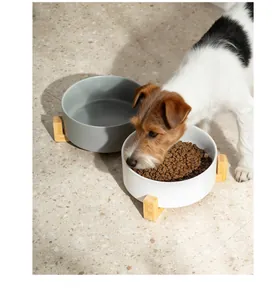 Detailansicht eines weißen Keramik-Fressnapfes mit Holzständer und einem essenden Hund