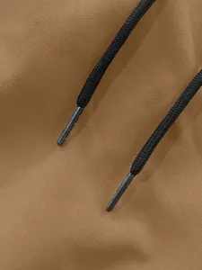 Dettaglio ravvicinato dei coulisse neri intrecciati sul tessuto di pantaloni cargo tan