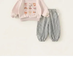 Dettaglio della felpa rosa per bambine con stampe animali e pantaloni grigi con fiocchi