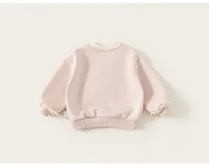 Dettaglio posteriore di una felpa rosa da bambina con eleganti polsini a balze