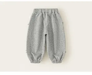 Dettaglio dei pantaloni sportivi grigi per bambine con graziosi fiocchi laterali.
