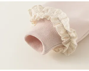 Dettaglio polsino felpa bambina con costine rosa e delicati volant in pizzo color crema.