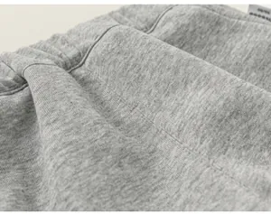 Primo piano del morbido tessuto grigio melange e della vita elastica di una felpa bimba.
