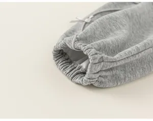 Dettaglio del polsino elastico con fiocchetto di una felpa grigia per bambini e neonati