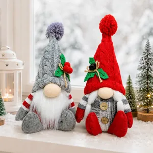 Zwei dekorative Plüsch-Weihnachtsgnome mit Strickmützen auf einem verschneiten Fenstersims
