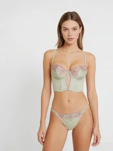 Completo intimo bustier in raso verde chiaro con dettagli ricamati a rosa su modella.