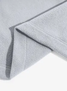 Dettaglio ravvicinato della trama in pile grigio e delle cuciture ordinate sull'orlo.