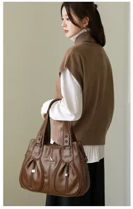 Macro view of a brown pebbled faux leather large tote bag carried by an Asian model