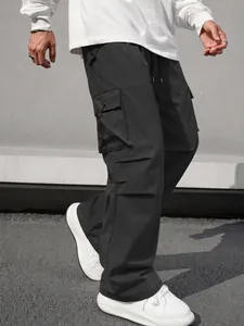 Detail view of men's black techwear cargo pants with multiple side pockets.