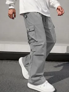 Detailed view of gray functional cargo pants with large side pockets and drawstring