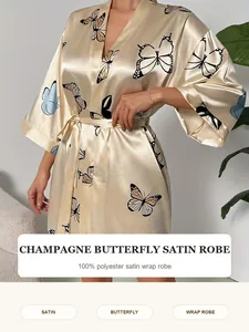 Detail van champagne satijnen ochtendjas met elegante vlinderprint en overslagontwerp