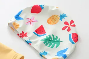 Detailed view of kids swim cap featuring vibrant tropical fruit and colorful flower patterns.