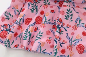 Macro view showing the vibrant pink floral pattern and ruffled skirt detail of girls swimsuit