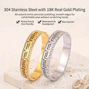Detail of 18K gold plated stainless steel bangles with Greek key pattern and crystals