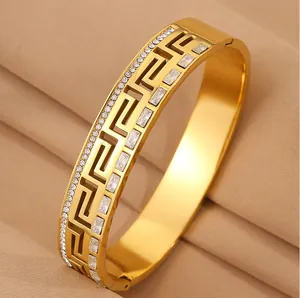 Detailed macro view of gold stainless steel bangle with Greek key pattern and crystals