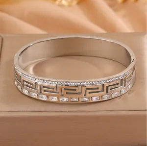 Detailed view of silver stainless steel bangle with meander pattern and crystals