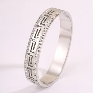 Close-up of vintage Greca pattern and inlaid crystals on silver stainless steel bangle