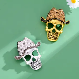 Detail shot of Halloween rhinestone skull brooches in gold and silver cowboy hats.