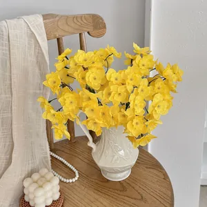 Detail of yellow simulation narcissus bouquet in a white embossed ceramic vase