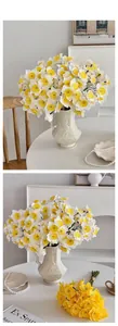 Detail view of lifelike artificial white and yellow narcissus flowers in a ceramic vase.