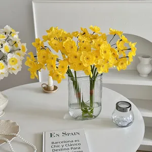 Vibrant yellow artificial narcissus flowers in a stylish ribbed glass vase home decor