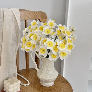 Realistic artificial daffodils bouquet in vintage cream ceramic pitcher for home decor.
