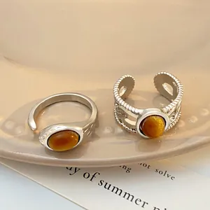 Detailed macro view of two silver adjustable rings featuring amber tiger eye oval stones