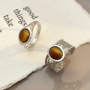 Detailed shot of vintage silver rings with oval tiger eye stones on textured paper