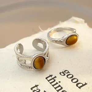 Macro shot of vintage silver rings featuring tiger eye stones on textured paper background
