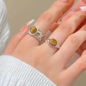 Detailed view of vintage silver rings featuring oval tiger eye stones on a hand