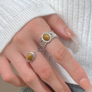 Close-up detail shot of a silver tiger eye stone ring set on a hand with a white sweater