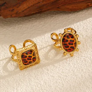 Macro view of leopard print rings with gold-toned bands on textured white surface.