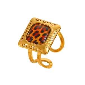 Macro view of adjustable gold-tone ring featuring a leopard print inlay and Greek key border