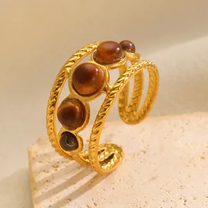 Macro view of a gold-plated multi-layer ring featuring five polished tiger eye stones.
