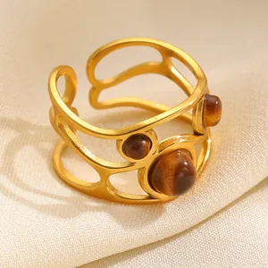 Detailed macro view of gold-tone hollow ring featuring polished brown tiger eye stones.