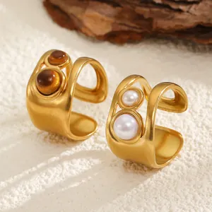 Macro shot of adjustable gold rings featuring tiger eye stones and elegant pearls.