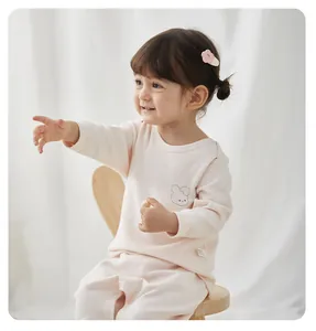 Toddler girl in pink pure cotton thermal pajama set sitting on a stool