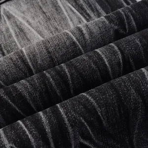 Close-up of premium washed black denim fabric texture for men's flared jeans.