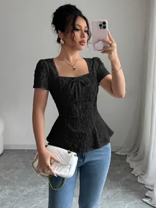 Detalle de un top de encaje negro con cuello cuadrado, lazo y bajo con volantes