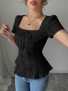 Vista detallada de una elegante blusa de encaje negro con cuello cuadrado y un lazo