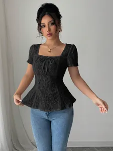 Detalle de un elegante top peplum de encaje negro con cuello cuadrado y lazo frontal