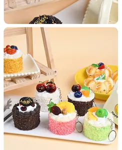 Close-up of assorted PU simulation mousse cake keychains with realistic fruit toppings.