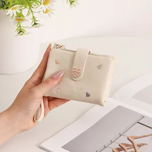 Close-up detail of a beige short folding wallet for women with heart embroidery and strap